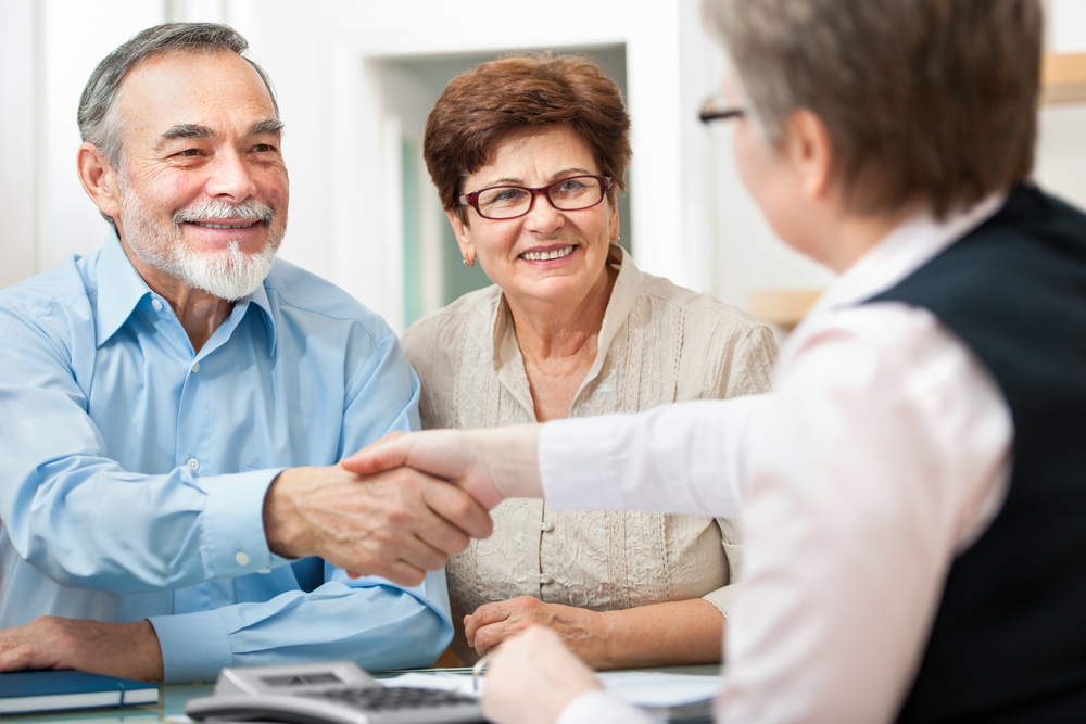 Senior,Couple,Smiling,While,Shaking,Hand,With,Financial,Advisor